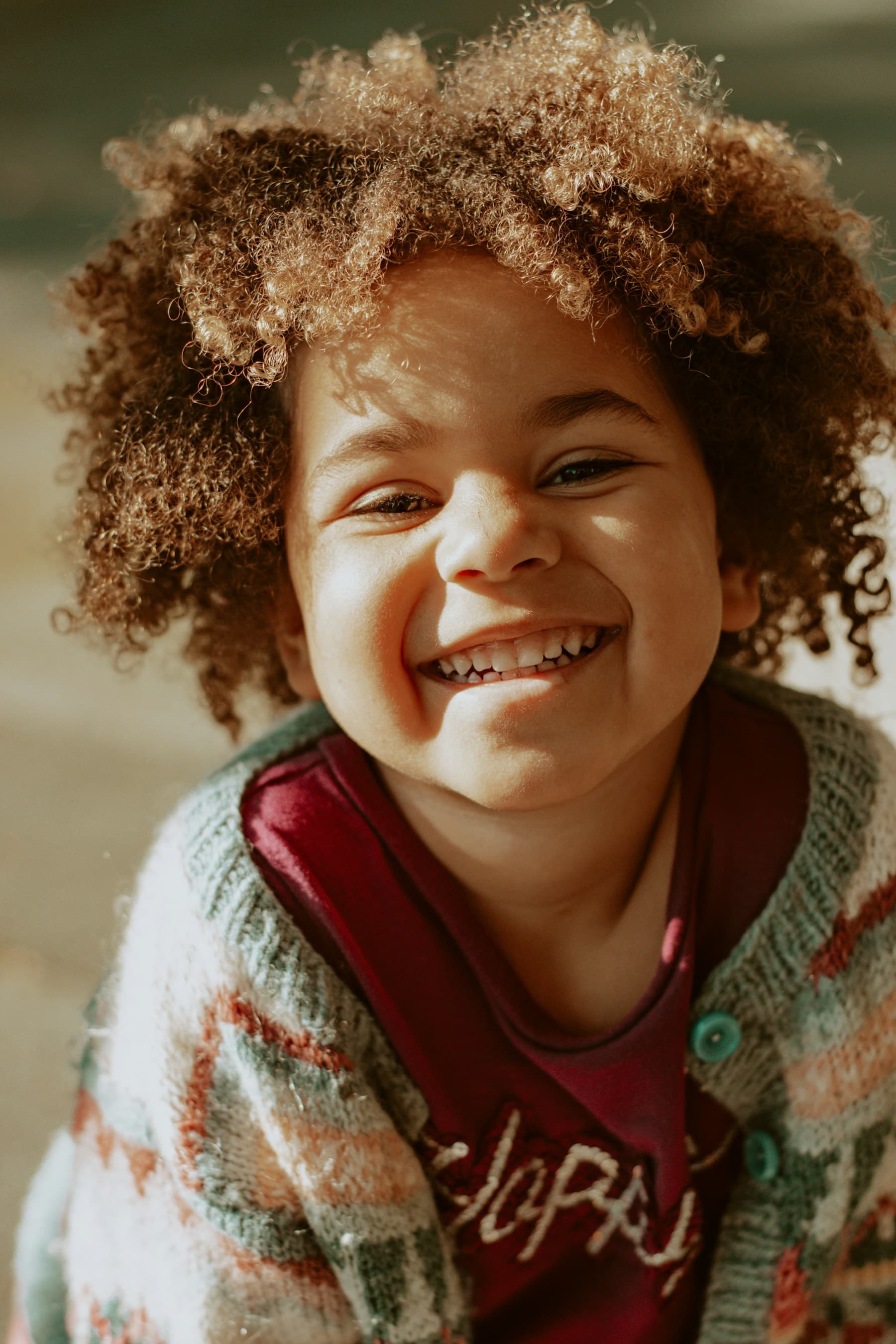 Criança sorrindo com cabelo cacheado