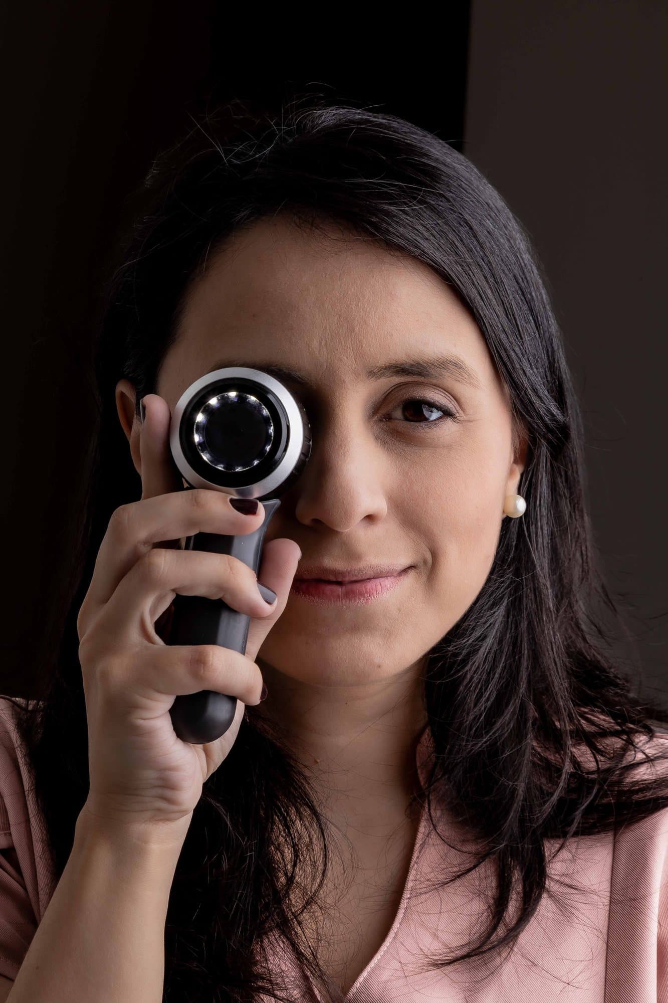 Dra. Paula Azevedo segurando o dermatoscópio junto ao rosto